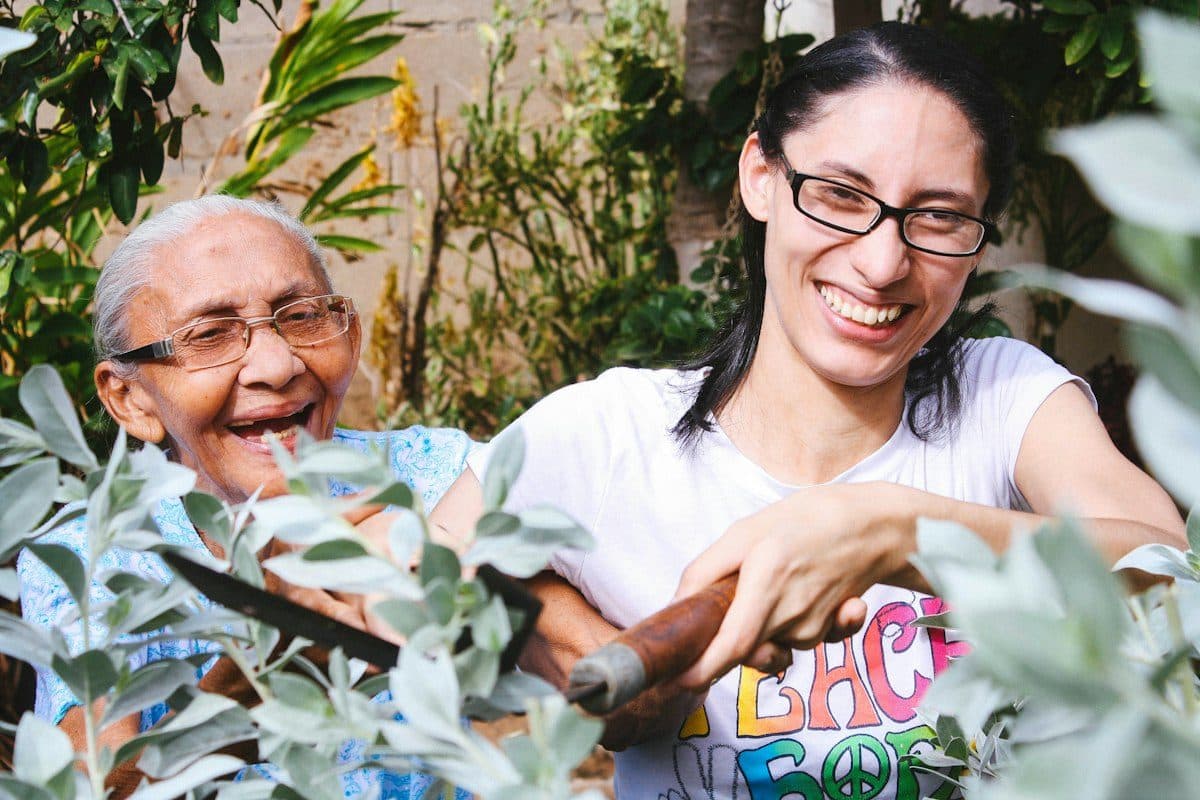 A senior mother and her adult daughter laughing together in a garden