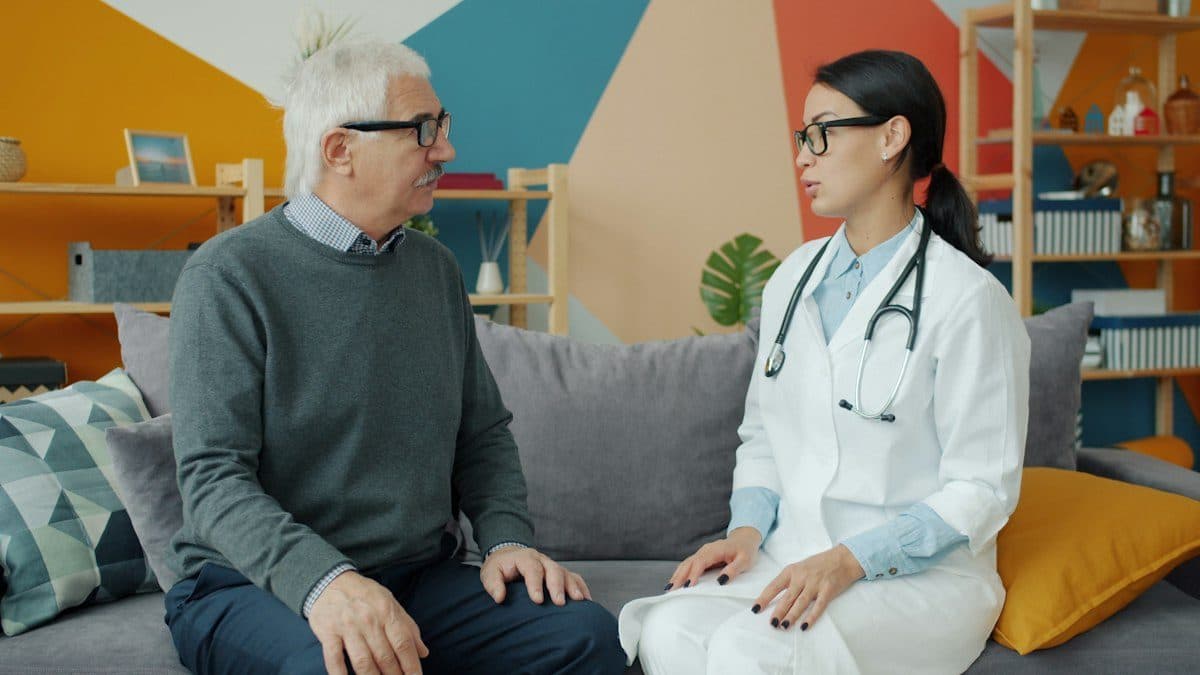 A clinician talking with an older patient on a couch